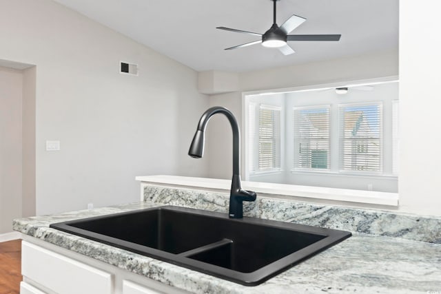 interior space featuring visible vents, a ceiling fan, vaulted ceiling, a sink, and wood finished floors