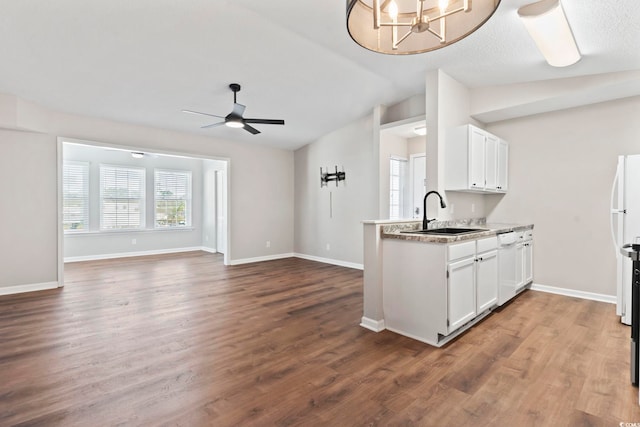 kitchen with vaulted ceiling, open floor plan, a sink, and white cabinetry