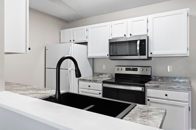 kitchen with stainless steel appliances, light countertops, and white cabinets