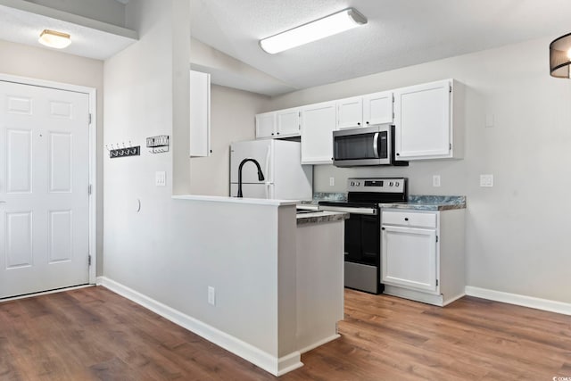 kitchen featuring baseboards, appliances with stainless steel finishes, white cabinets, and wood finished floors