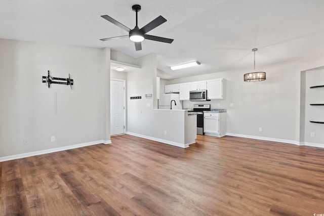 kitchen with wood finished floors, white cabinets, open floor plan, light countertops, and appliances with stainless steel finishes