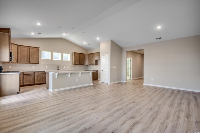 179 Glengrove Ln, Murrells Inlet, SC 29576 - kitchen featuring open floor plan, vaulted ceiling, a center island, light wood-style flooring, and brown cabinets