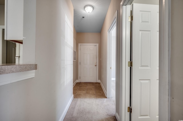 corridor with baseboards and light colored carpet