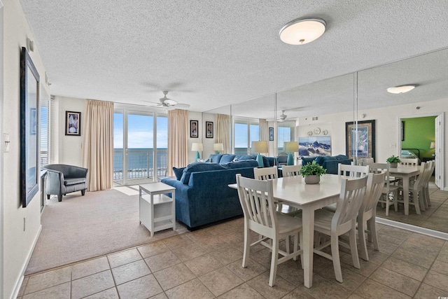 dining space with ceiling fan, a textured ceiling, and a water view