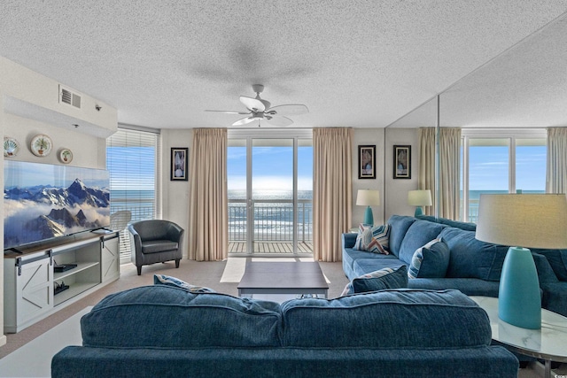 carpeted living room featuring ceiling fan, a textured ceiling, plenty of natural light, and visible vents