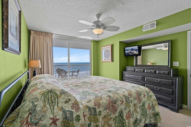 carpeted bedroom featuring a textured ceiling, a ceiling fan, visible vents, and access to exterior