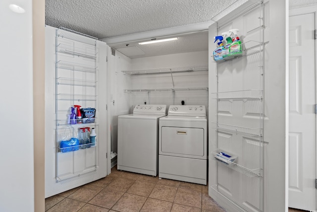 clothes washing area with a textured ceiling, laundry area, light tile patterned floors, and washing machine and clothes dryer