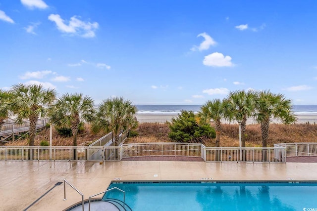 pool with a water view, fence, and a patio