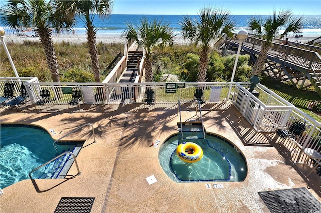 community pool featuring a community hot tub, a water view, a patio, and stairs