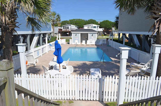 community pool with a patio, an outdoor structure, and fence private yard