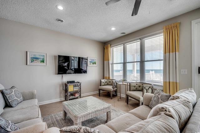 living area featuring light tile patterned floors, a textured ceiling, visible vents, and baseboards