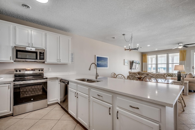 kitchen with light countertops, appliances with stainless steel finishes, light tile patterned flooring, a sink, and a peninsula