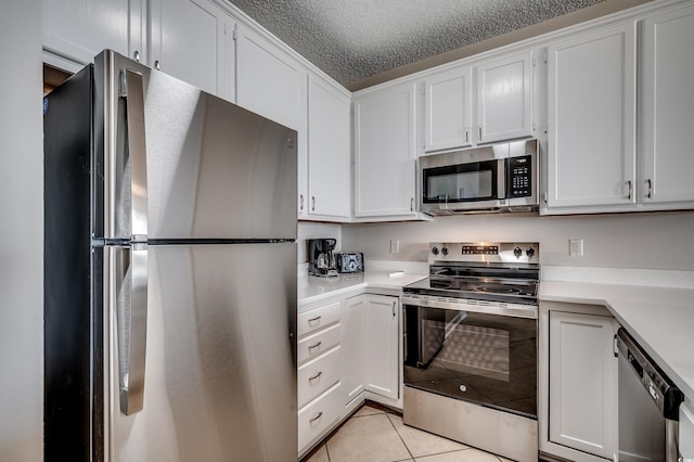 kitchen with stainless steel appliances, white cabinets, light tile patterned flooring, and a textured ceiling