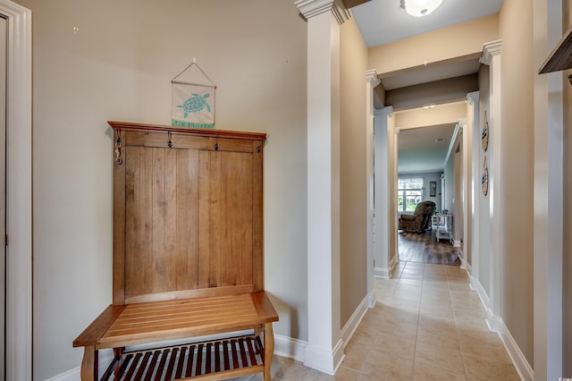 mudroom with decorative columns, light tile patterned floors, and baseboards