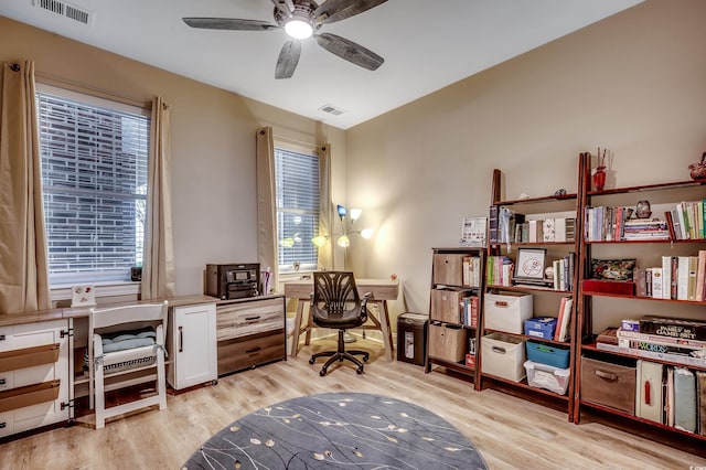 office area featuring light wood finished floors, visible vents, and a ceiling fan