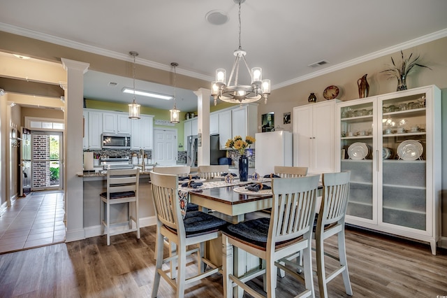 dining room featuring a notable chandelier, visible vents, crown molding, and wood finished floors