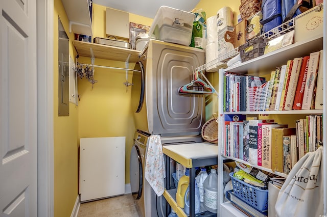 clothes washing area featuring tile patterned flooring, stacked washer and dryer, laundry area, and baseboards