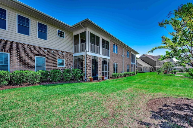 rear view of property featuring a yard and brick siding