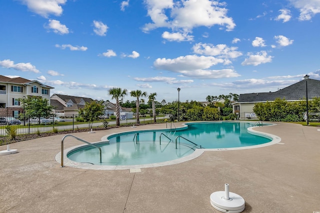pool with a patio, a residential view, and fence
