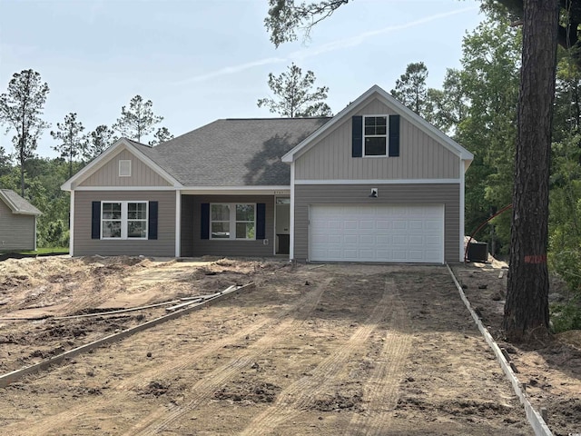 view of front of house featuring dirt driveway, a garage, board and batten siding, and a shingled roof