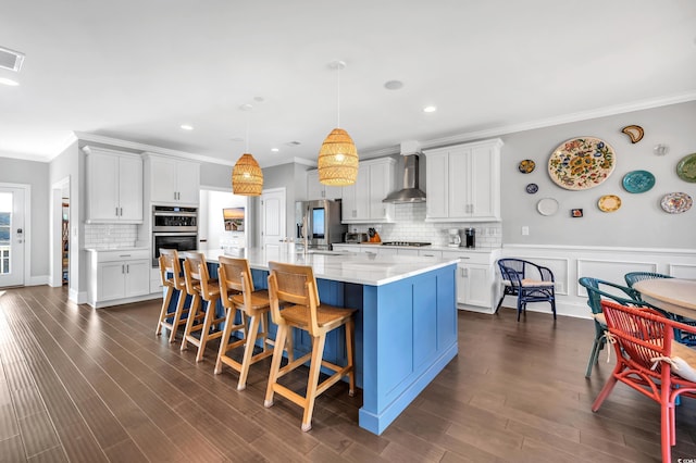 kitchen featuring a sink, light countertops, appliances with stainless steel finishes, wall chimney exhaust hood, and dark wood finished floors