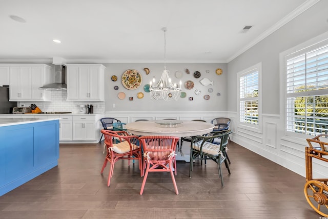 dining room featuring dark wood-style floors, a wainscoted wall, a notable chandelier, visible vents, and ornamental molding