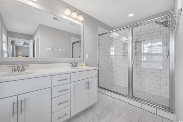 full bath with visible vents, a sink, a shower stall, and double vanity