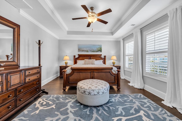 bedroom with visible vents, baseboards, a raised ceiling, dark wood finished floors, and crown molding