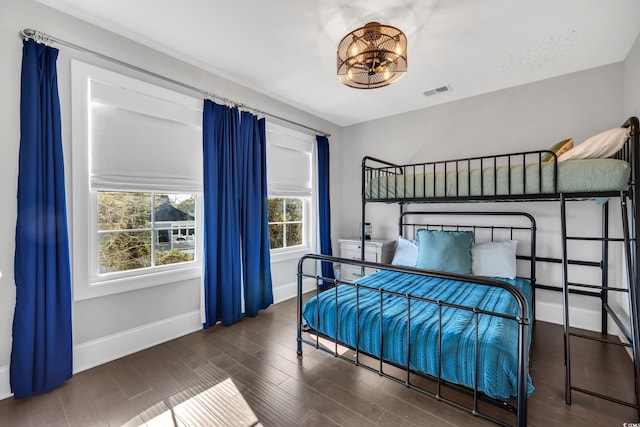 bedroom with visible vents, baseboards, and wood finished floors