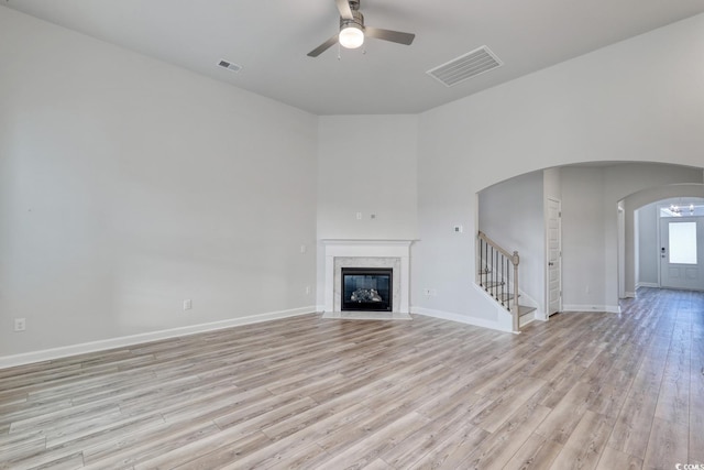 4036 Bucolic Loop, Myrtle Beach, SC 29588 - unfurnished living room with ceiling fan, arched walkways, stairs, light wood-type flooring, and a fireplace