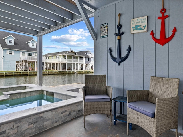 view of patio featuring an in ground hot tub, a water view, and a residential view