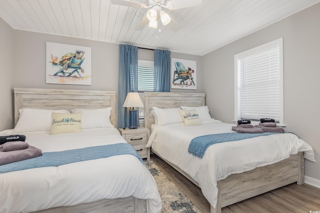 bedroom with baseboards, wood finished floors, wood ceiling, and a ceiling fan