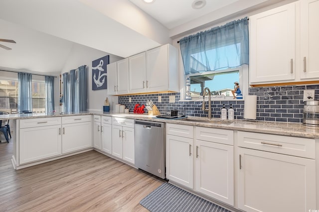 kitchen with light wood finished floors, white cabinets, dishwasher, a peninsula, and a sink