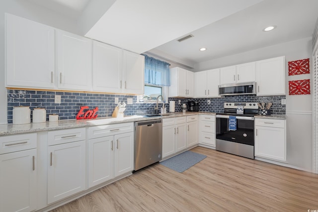 kitchen with appliances with stainless steel finishes, white cabinetry, visible vents, and light wood-style floors