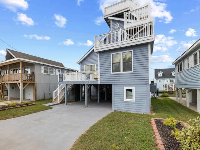 back of house with a yard, a carport, stairway, and concrete driveway