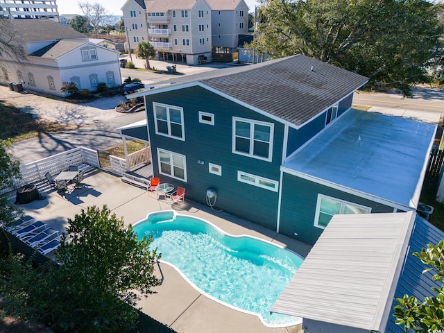 back of property with an outdoor pool and a patio