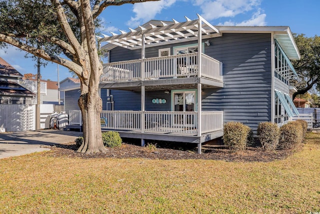 rear view of house with a balcony, a pergola, and a lawn