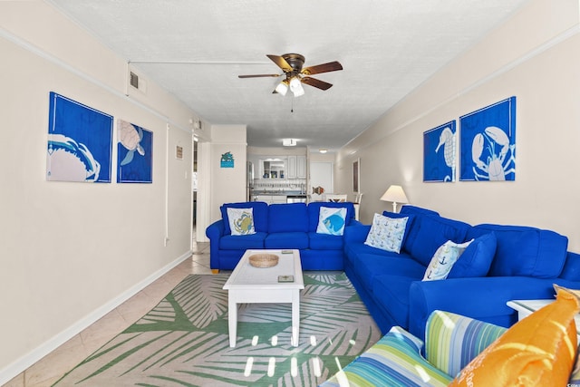 living room featuring tile patterned flooring, ceiling fan, a textured ceiling, and baseboards