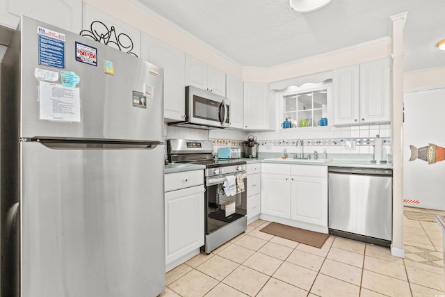 kitchen featuring stainless steel appliances, white cabinets, a sink, and decorative backsplash