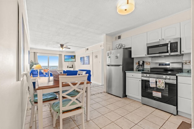 kitchen with stainless steel appliances, white cabinets, a textured ceiling, and a ceiling fan