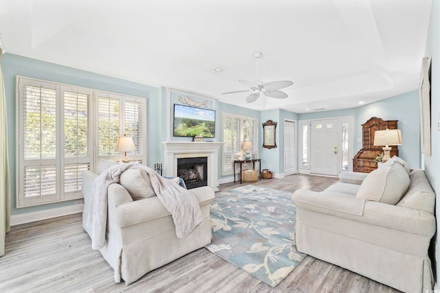 living room with light wood finished floors, baseboards, ceiling fan, a fireplace, and recessed lighting