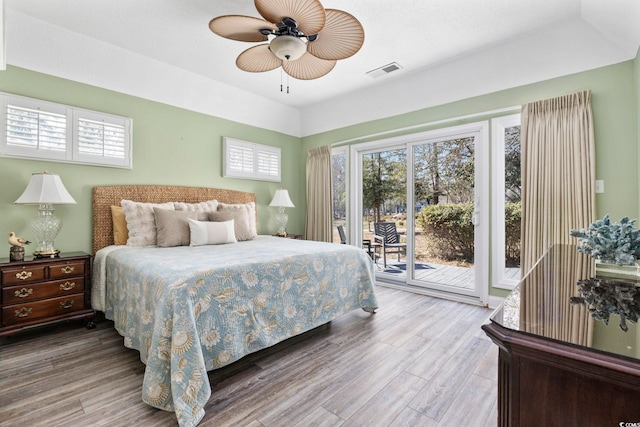 bedroom with access to exterior, visible vents, ceiling fan, and wood finished floors