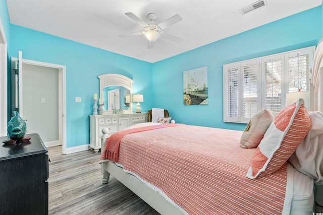 bedroom with a ceiling fan, baseboards, visible vents, and wood finished floors