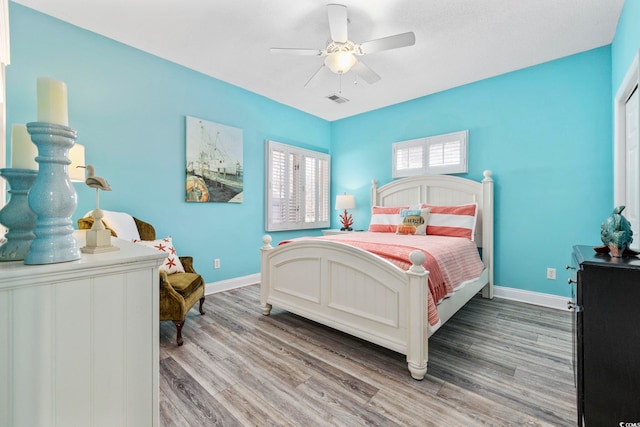 bedroom featuring light wood-type flooring, visible vents, ceiling fan, and baseboards