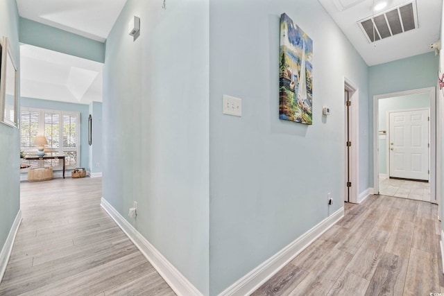 corridor featuring light wood finished floors, visible vents, and baseboards