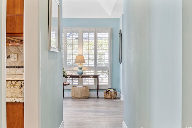 hall featuring light wood-style flooring and baseboards