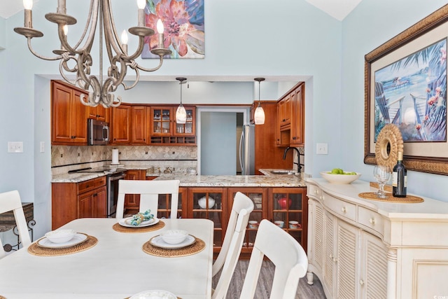 kitchen featuring brown cabinetry, glass insert cabinets, appliances with stainless steel finishes, a sink, and backsplash