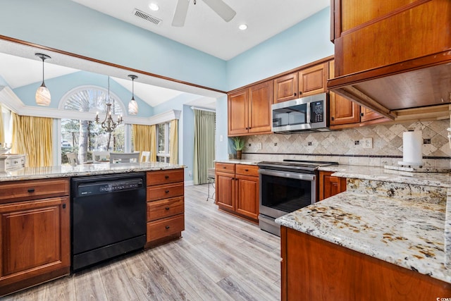 kitchen featuring visible vents, brown cabinets, light stone countertops, vaulted ceiling, and stainless steel appliances