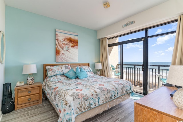 bedroom with access to outside, multiple windows, a water view, and wood tiled floor