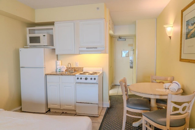 kitchen with white cabinets, white appliances, under cabinet range hood, and light tile patterned floors